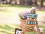 a rustic wedding decoration of a ladder, some signs and artworks, photos and pastel blooms in pots