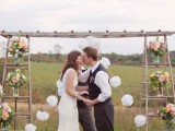 a creative wedding arch made of two ladders, pompoms, pink blooms in jars