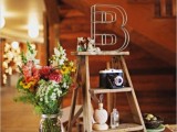 a mini ladder decoration with cameras, vases, a wire letter and some figurines and blooms
