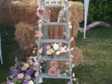 a rustic wedding decoration of a grey ladder, pastel and bright blooms, woven hearts and Mr and Mrs signs