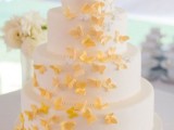 a neutral wedding cake with yellow butterflies is a lovely and chic idea of a wedding dessert with plenty of color