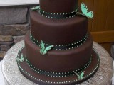 a chocolate wedding cake with brown and green ribbons and bold green butterflies looks bold, cool and very chic
