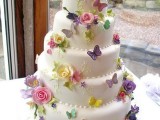 a whimsical wedding cake decorated with colorful sugar butterflies and blooms is a bright and catchy idea, it looks very interesting