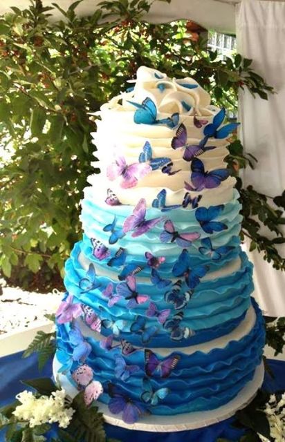 a colorful ombre wedding cake from white to bright blue, with bold purple and blue butterflies for detailing is a gorgeous idea for a fairy-tale wedding