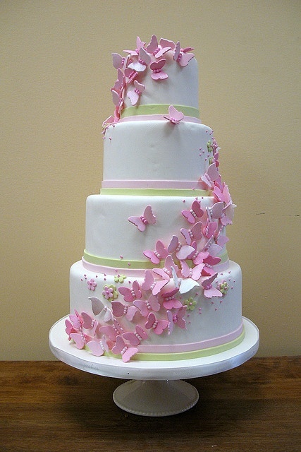 a white wedding cake decorated with pink butterflies and pastel sugar ribbons is a great idea for a fairy tale wedding