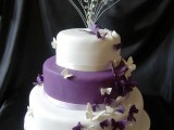 a purple and white wedding cake topped with crystals, twigs and decorated with purple and white butterflies is a bold and catchy idea
