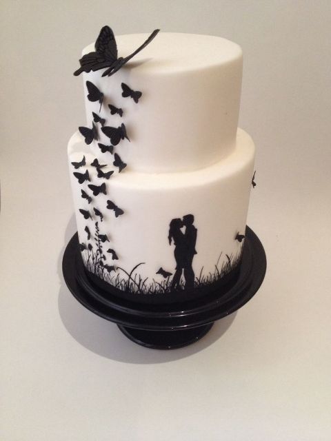 a black and white wedding cake decorated with black butterflies and with a romantic kissing scene painted on it is a gorgeous statement dessert idea