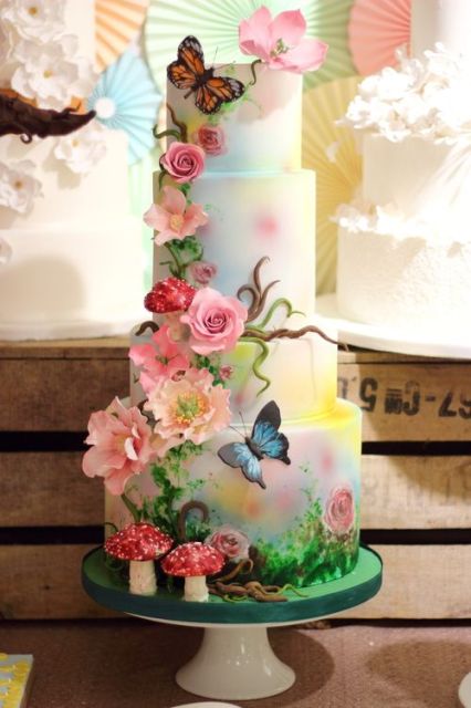 a whimsical fairy-tale wedding cake with bright painted blooms and branches, with sugar blooms and butterflies all over the cake is a catchy idea