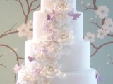 a white wedding cake decorated with white sugar blooms and lilac butterflies is a lovely and very sweet idea for your wedding