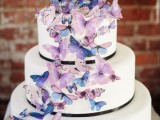 a romantic white wedding cake with black ribbons and watercolor butterflies in lilac and blue is a beautiful and chic idea