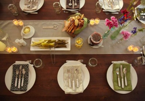 a simple and cute bbq rehearsal dinner tablescape with a striped table runner, candles, printed napkins, bright blooms and some appetizers and dips