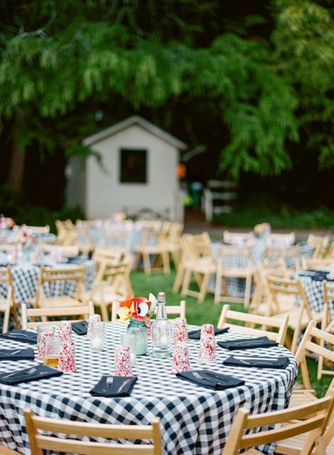 a cute bbq rehearsal dinner reception with round tables with plaid tablecloths, navy napkins, colorful glasses and dips and sauces