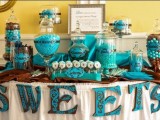a turquoise and brown candy bar with letter banners, large glass jars with candies and a sign