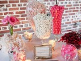 a small candy table with pink blooms, candles and some candies in various jars