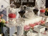 an elegant black and white candy bar with colorful candies, blooms and a sign printed out