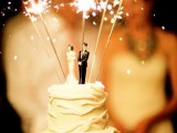 a neutral and textural wedding cake topped with couple cake toppers and sparklers is a lovely idea for a wedding