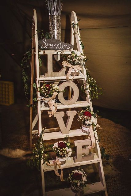 a neutral ladder with letters, white blooms and greenery, sparklers offered to the guests - as wedding favors or for your send off
