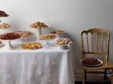 a vintage inspired cookie table with a tablecloth and lights plus simple stands with cookies and sweets