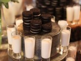 a rustic cookie bar with a stained table and metal stands with milk glasses and cookies