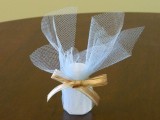 a wedding favor – a candle with white tulle plus a mustard ribbon bow for a cozy wedding