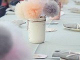 a white jar with colorful tulle pompoms is an idea of an expensive wedding centerpiece