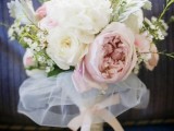 a lush pastel and neutral wedding bouquet with a tulel wrap and a bow