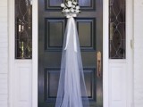 a floral arrangement with a bow and tulle on the door of your home on the day of your wedding