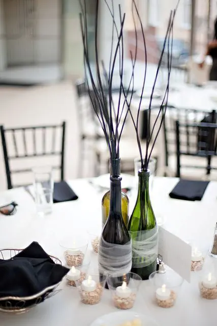 bottles wrapped with tulle and branches for a simple and casual wedding centerpiece