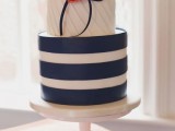 a wedding cake with a navy and white striped tier, white draped tiers, coral sugar blooms is a cool idea for a nautical wedding