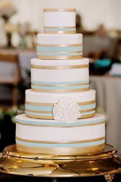an elegant and vintage-inspired white, aqua and gold striped wedding cake with a single white sugar bloom for a vintage wedding
