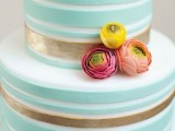 a mint and gold striped wedding cake decorated with pink and yellow ranunculus is a stylish and chic idea for a spring wedding