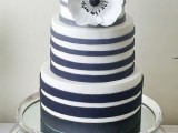 a striped wedding cake with black and white and grey and white striped and a sugar bloom is a cool and bold idea for a monochromatic wedding
