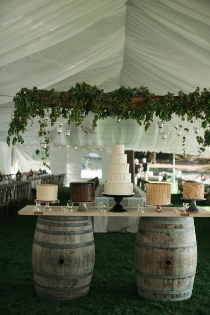 a wedding dessert station of wine barrels and a countertop plus several wedding cakes is a pretty and very easy idea