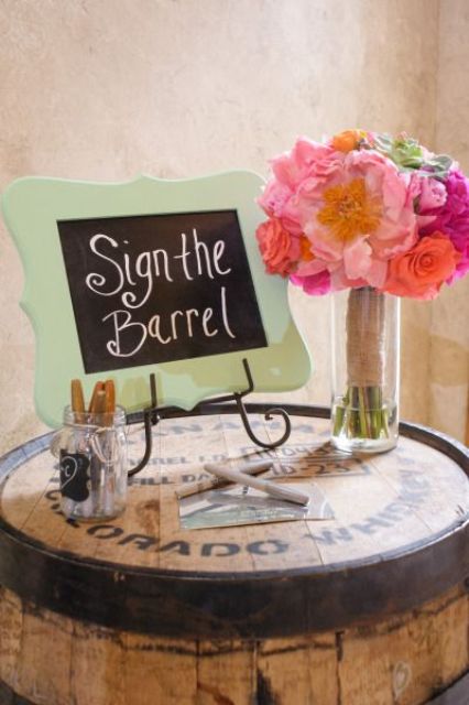 a wine barrel instead of a usual wedding guest book with bright blooms, a chalkboard sign, pens