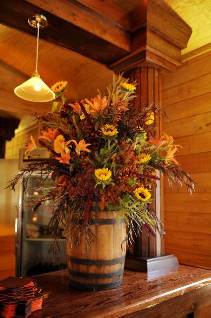 a small barrel used as a vase for a super bright rustic wedding floral arrangement
