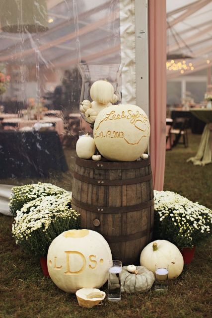 a barrel with white pumpkins, candles and blooms around is a lovely rustic or farmhouse wedding decoration
