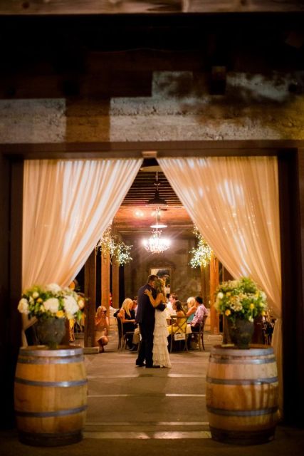 wine barrels turned into floral stands with lush arrangements and curtains on sides are great