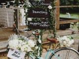 a mint green bike with stained signs, greenery and white blooms is a stylish idea for a modern rustic wedding