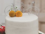 a white buttercream wedding cake decorated with a wire bike and a billy ball and a yellow bloom is a lovely idea for a spring or summer wedding