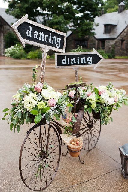 a bike decorated with greenery, white and pink blooms and chalkboard signs is a lovely spring or summer wedding decoration