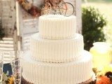 a white textural buttercream wedding cake topped with a bike is a stylish and fun solution for a wedding