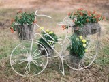a white bike with greenery and bold blooms is a pretty and easy decoration for any outdoor wedding, make it yourself