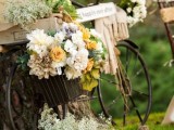 a vintage bike decorated with lush blooms and greenery, with a box filled with greenery and blooms, a blanket and a sign is a simple and lovely decoration