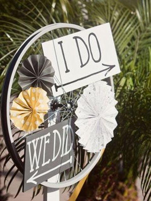a vintage bike wheel decorated with signs and with paper fans is a cool decoration for any relaxed wedding