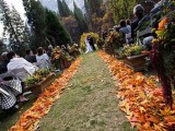 an outdoor wedding aisle with bright fall leaves lining it instead of blooms is a cool idea for a fall rustic wedding