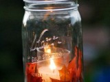 a fall candle lantern of a larger jar with fall leaves and a candle in a smaller glass inside is a very cozy idea for a fall wedding