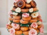 a donut tower with fresh blooms in pink and white is a cute casual substitute for a traditional wedding cake