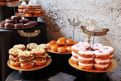 gilded trays with lots of glazed donuts and cute toppers are a nice idea for a wedding dessert table