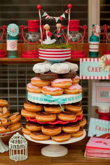 a simple and cute stand with lots of glazed donuts, moss, a fun topper with a banner for a casual wedding