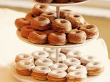 an elegant whte stand with lots of glazed donuts and signage is a stylish idea for every wedding